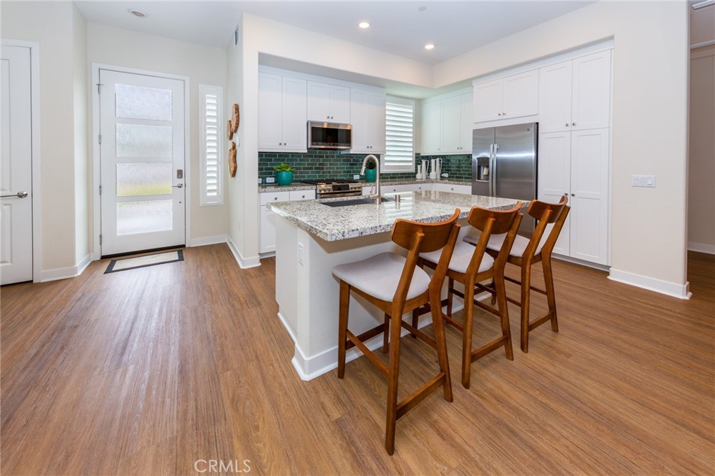 27466 Mercantile Court, Unit 101 Valencia, CA 91381 - Photo 3 of 21 an open kitchen with wooden floor and stainless steel appliances