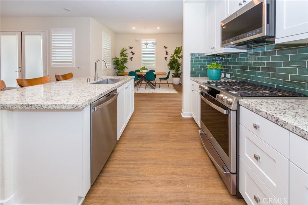 27466 Mercantile Court, Unit 101 Valencia, CA 91381 - Photo 5 of 21 a kitchen with stainless steel appliances granite countertop a stove a sink and a microwave
