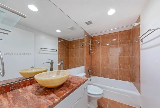 a bathroom with a granite countertop sink a toilet a mirror and bathtub