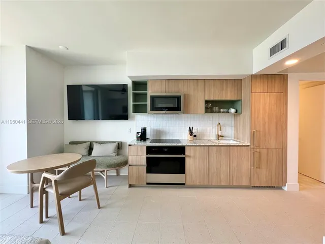 a living room with stainless steel appliances furniture a stove a microwave a sink and a refrigerator