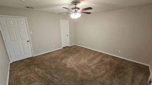 an empty room with closet and a ceiling fan