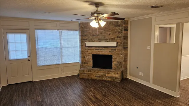 a view of an empty room with wooden floor fireplace and a window