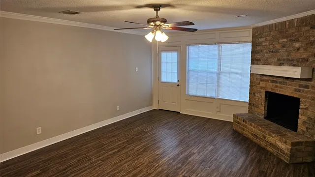 a view of an empty room with wooden floor fireplace and a window