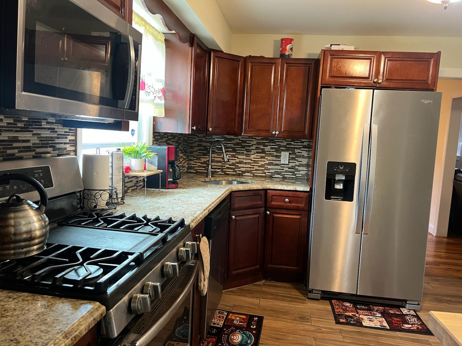 182 Long Beach Road Hempstead, NY 11550 - Photo 9 of 24 a kitchen with stainless steel appliances granite countertop a stove top oven a refrigerator and a microwave