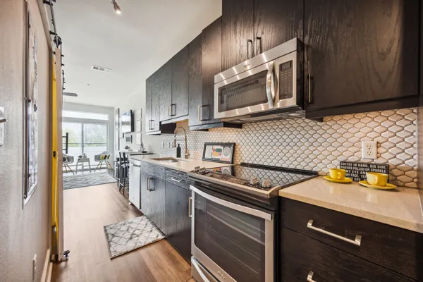 a kitchen with stainless steel appliances a sink a stove a microwave cabinets and a counter top space