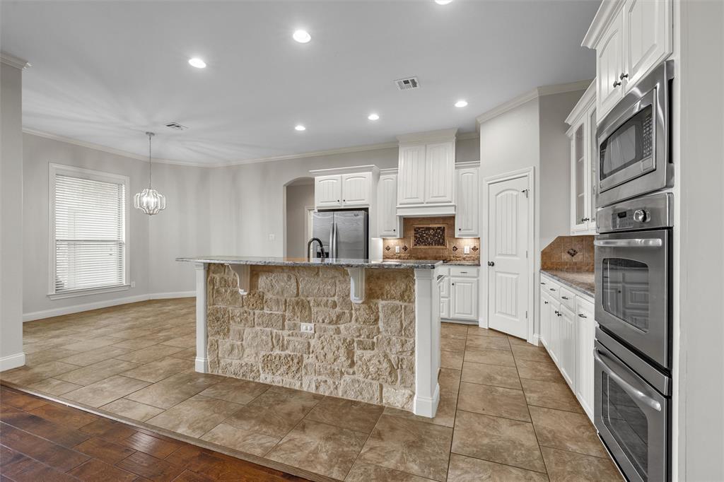 144 Ellis Farm Road Hewitt, TX 76643 - Photo 9 of 36 Gourmet kitchen featuring a stone-clad island, white cabinetry, integrated stainless steel appliances, and tile flooring