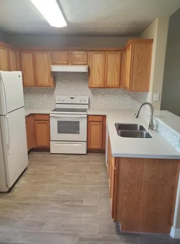 a kitchen with granite countertop a sink stove and refrigerator