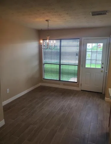 an empty room with wooden floor cabinet and window