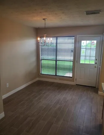 an empty room with wooden floor cabinet and window