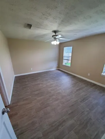 an empty room with windows and ceiling fan