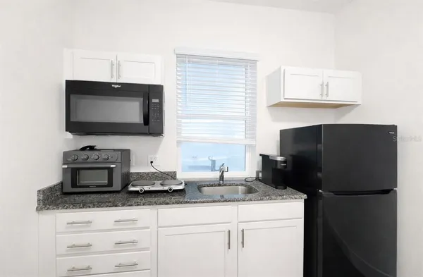 a kitchen with granite countertop a refrigerator and a stove top oven