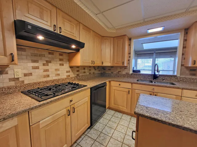 a kitchen with stainless steel appliances granite countertop a stove a sink and a microwave