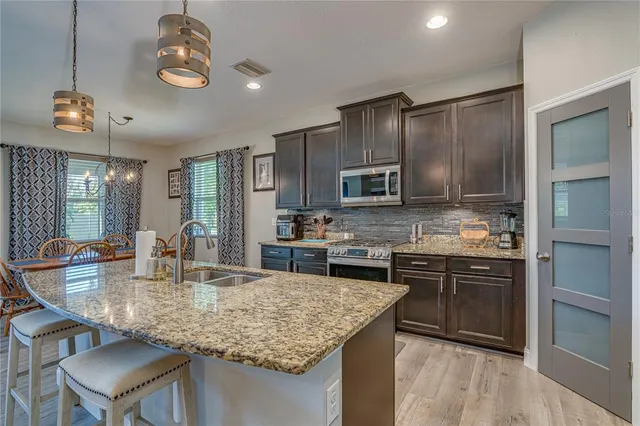 a kitchen with kitchen island granite countertop stainless steel appliances a sink center island and cabinets