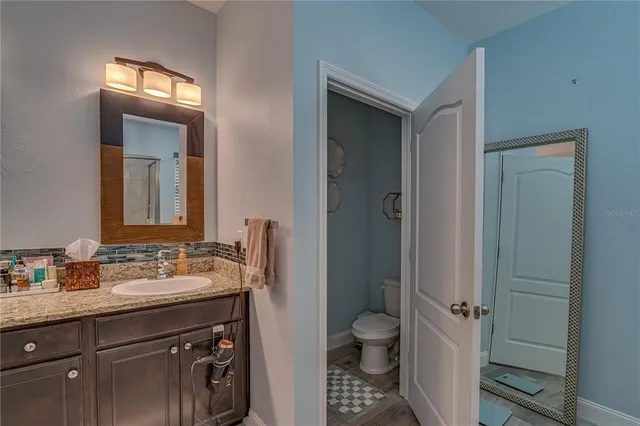 a bathroom with a granite countertop sink toilet a mirror and shower