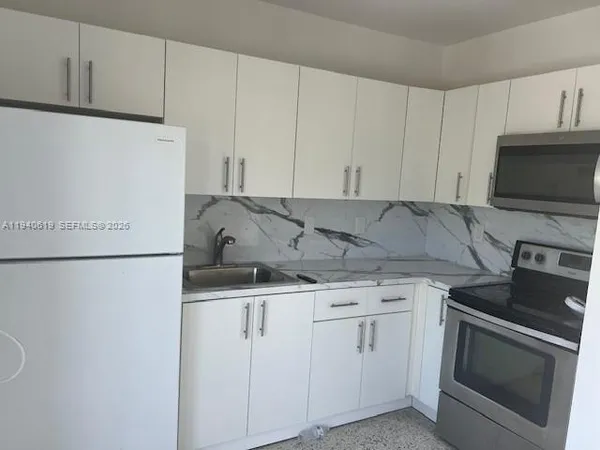a kitchen with granite countertop white cabinets and stainless steel appliances