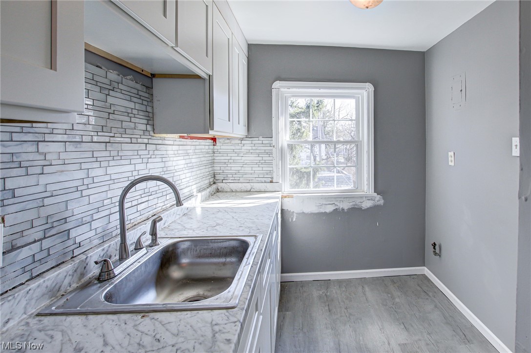 3423 Westbury Road Cleveland, OH 44120 - Photo 6 of 38 Kitchen featuring white cabinets, light wood-type flooring, sink, and tasteful backsplash