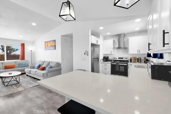 a living room with stainless steel appliances kitchen island furniture and a chandelier