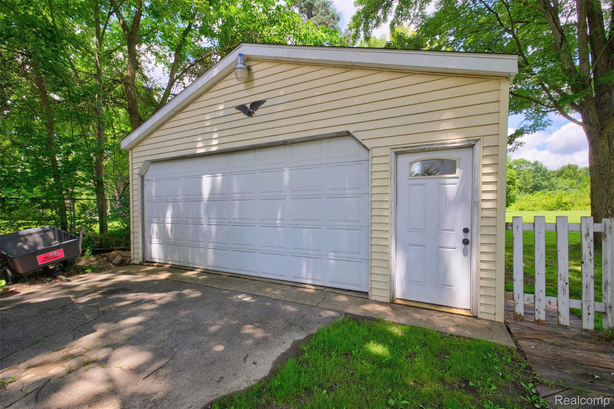 5244 Oleksyn Road Flint, MI 48504 - Photo 51 of 70 Detached garage with horizontal siding, a paneled garage door, and a separate side entry door with an arched window