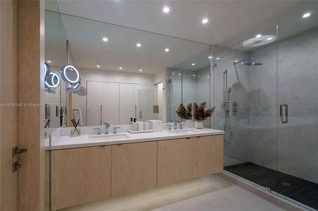 a bathroom with a double vanity sink a large mirror and shower