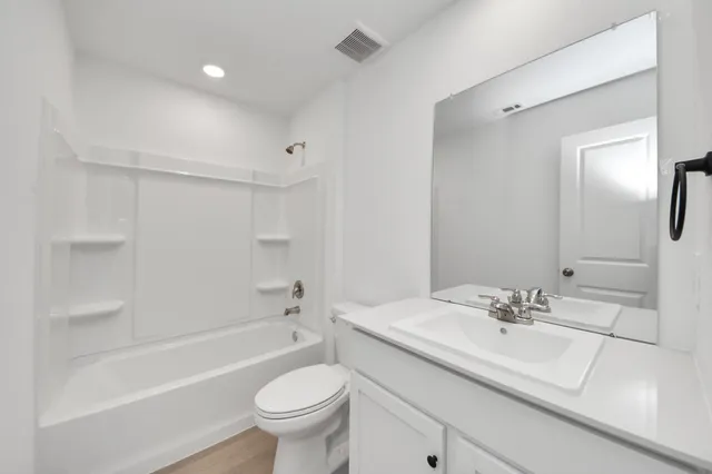 a bathroom with a shower sink vanity mirror and toilet