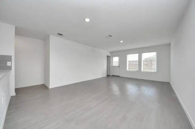 a view of an empty room with a window and wooden floor