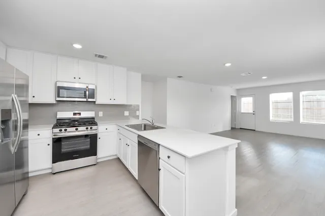 a kitchen with stainless steel appliances granite countertop a sink a stove and a refrigerator