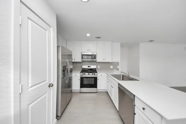a kitchen with white cabinets and stainless steel appliances