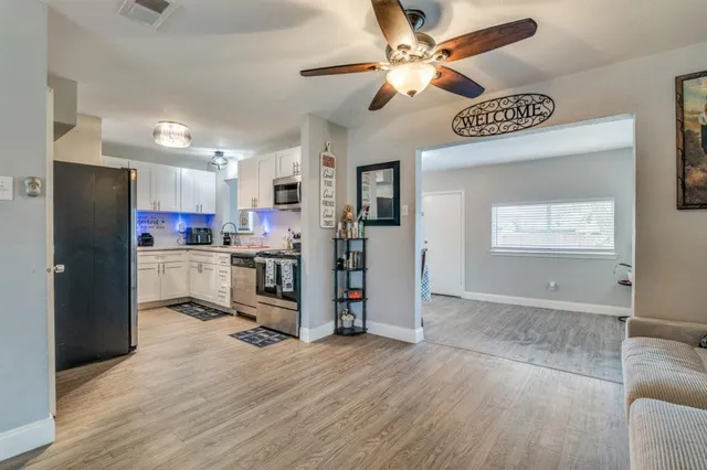 a view of a kitchen with a refrigerator a kitchen island wooden floor and a ceiling fan