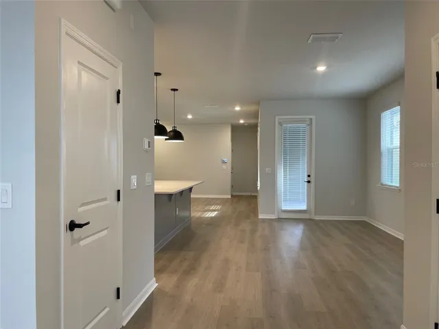 a view of a hallway with wooden floor and a bathroom