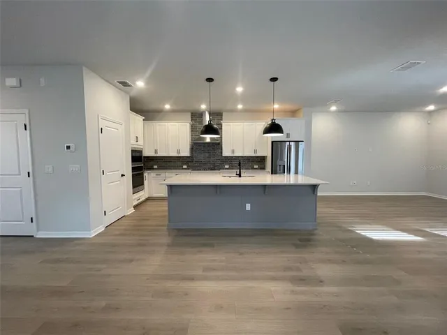 a view of kitchen with kitchen island stainless steel appliances sink refrigerator and microwave