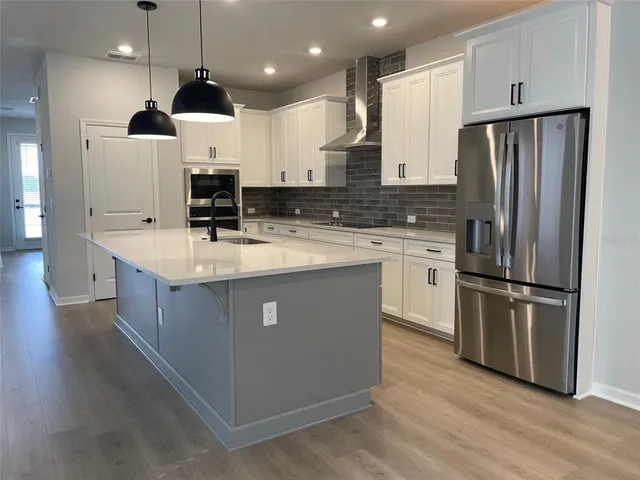 a kitchen with stainless steel appliances granite countertop a refrigerator a sink a stove and a wooden floors