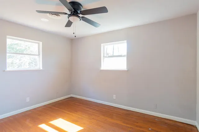 an empty room with a window and a fan