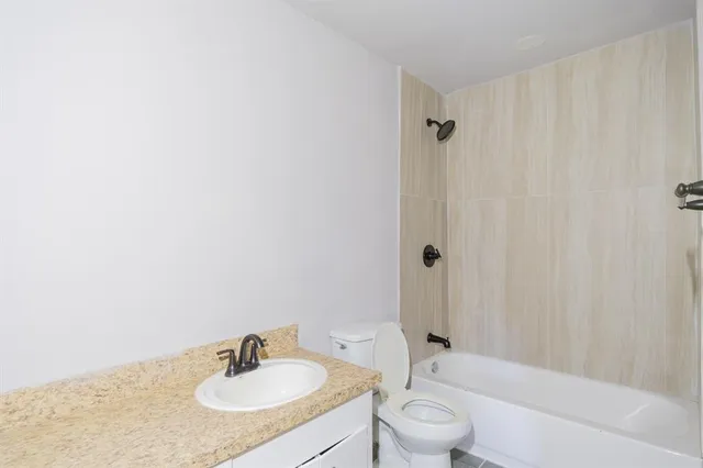 a bathroom with a granite countertop sink toilet a mirror and shower