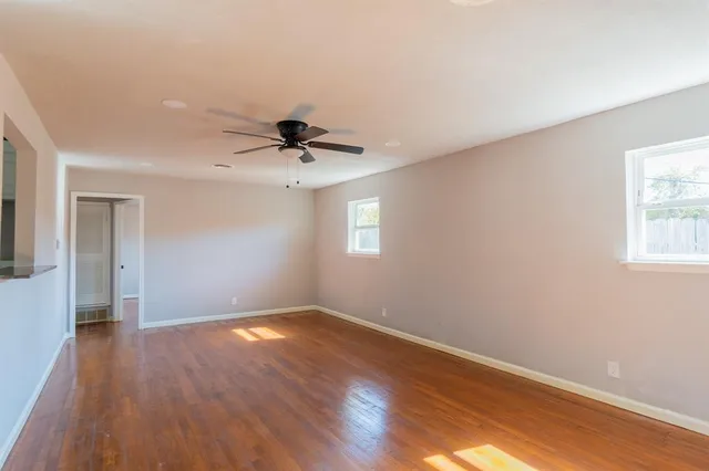 a view of a big room with wooden floor and windows