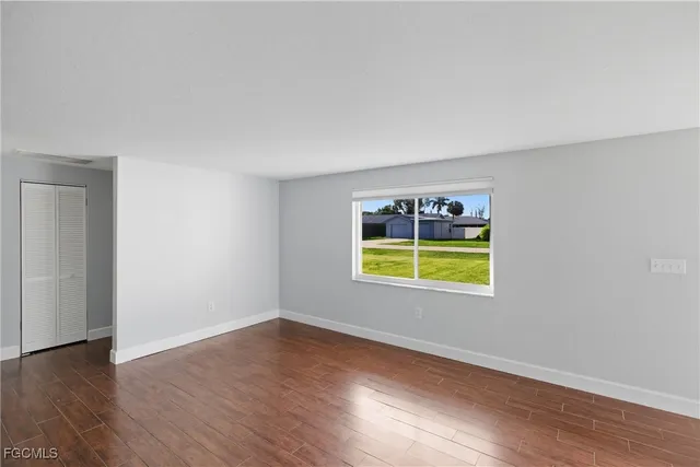 an empty room with a window and wooden floor