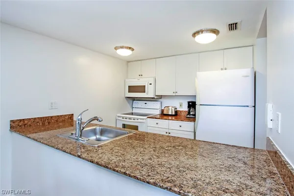 a kitchen with granite countertop a sink stove and cabinets