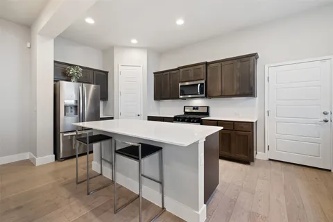 a kitchen with stainless steel appliances a stove a sink a microwave a refrigerator and cabinets