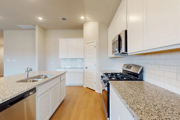 a kitchen with stainless steel appliances granite countertop a sink stove and cabinets
