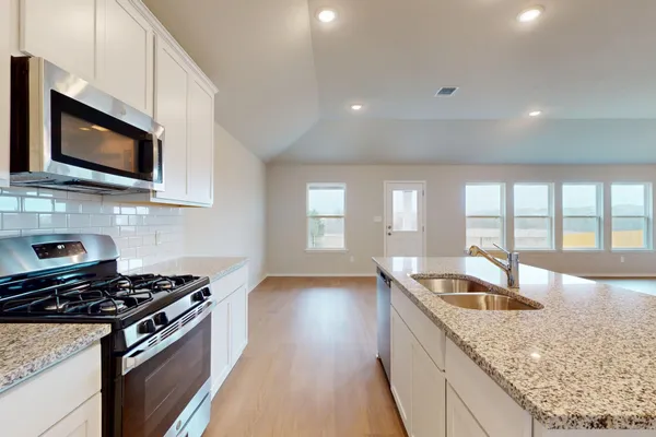 a kitchen with granite countertop a sink and a stove top oven