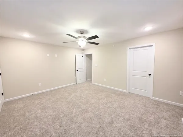 a view of an empty room with a chandelier fan