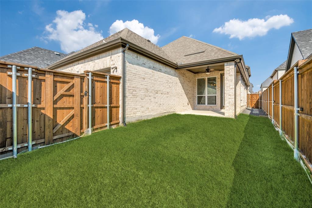 15621 Fringe Tree Road Frisco, TX 75035 - Photo 17 of 18 Back of property with a ceiling fan, roof with shingles, a gate, a patio, and brick siding