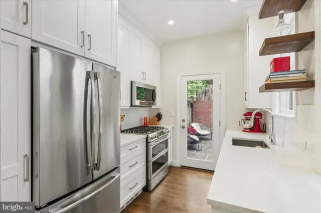 a kitchen with stainless steel appliances a refrigerator and a wooden floor
