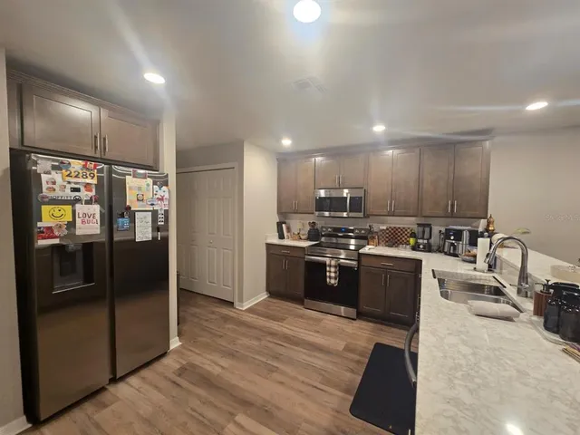 a large white kitchen with stainless steel appliances kitchen island a sink table and chairs