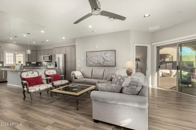 a living room with furniture kitchen view and a wooden floor