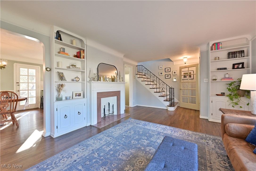 21887 Eaton Road Cleveland, OH 44126 - Photo 5 of 34 Living area featuring built in shelves, stairway, dark wood-style flooring, and a chandelier