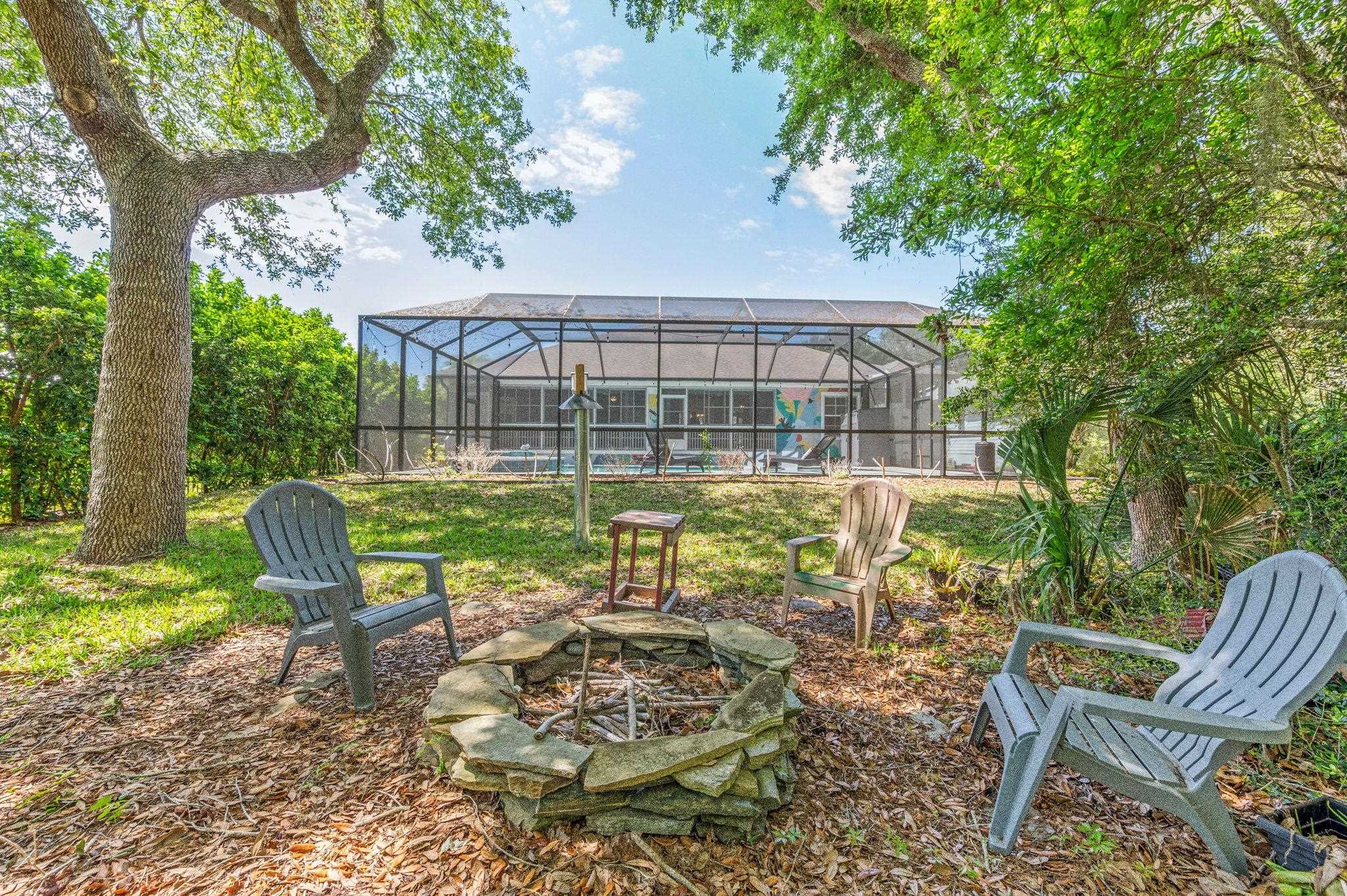 1184 Overdale Road St. Augustine, FL 32080 - Photo 29 of 75 View of green lawn featuring a sunroom, glass enclosure, an outdoor fire pit, and a patio area