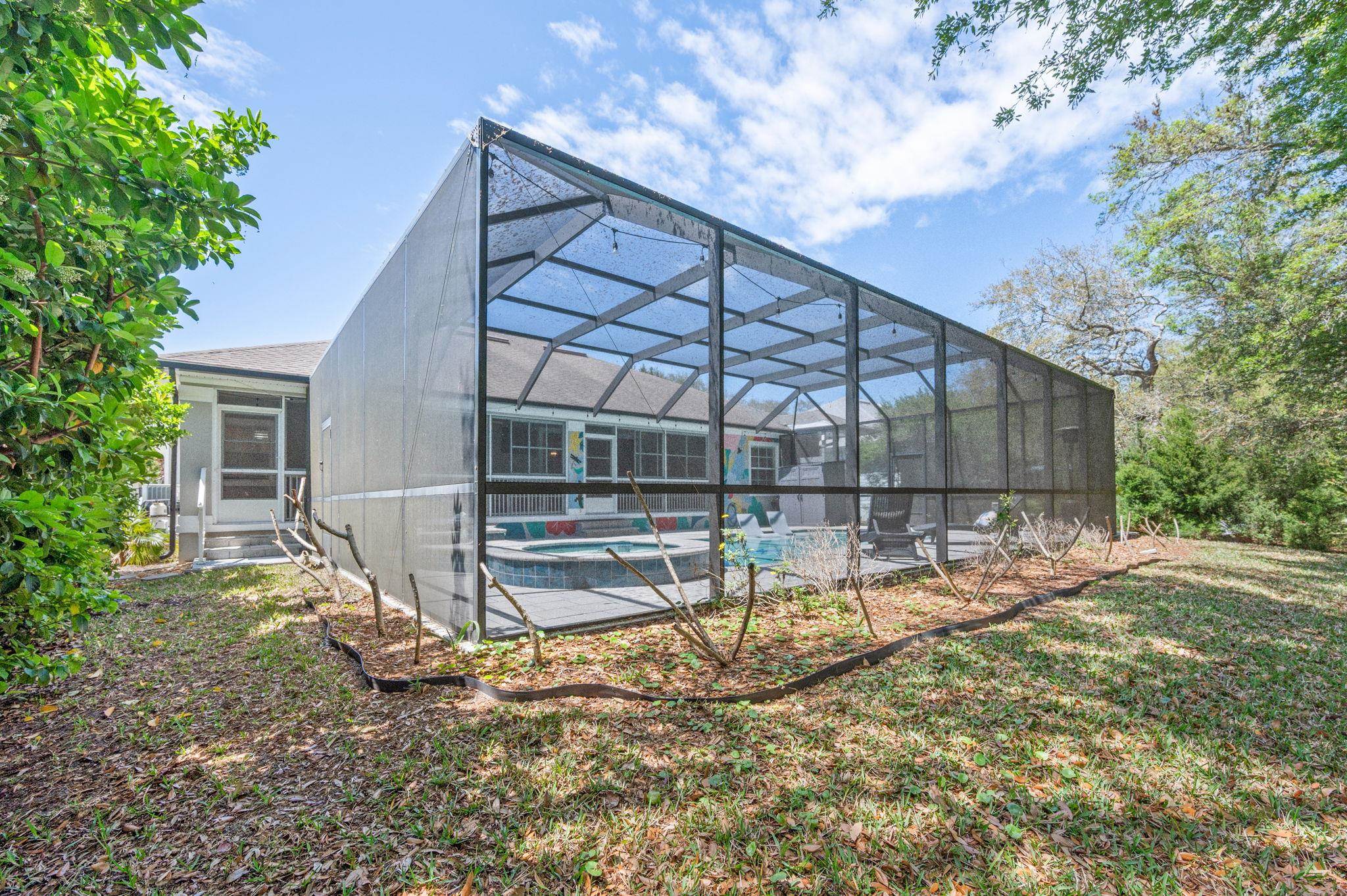1184 Overdale Road St. Augustine, FL 32080 - Photo 70 of 75 Rear view of house featuring a sunroom, glass enclosure, a pool with connected hot tub, and a patio