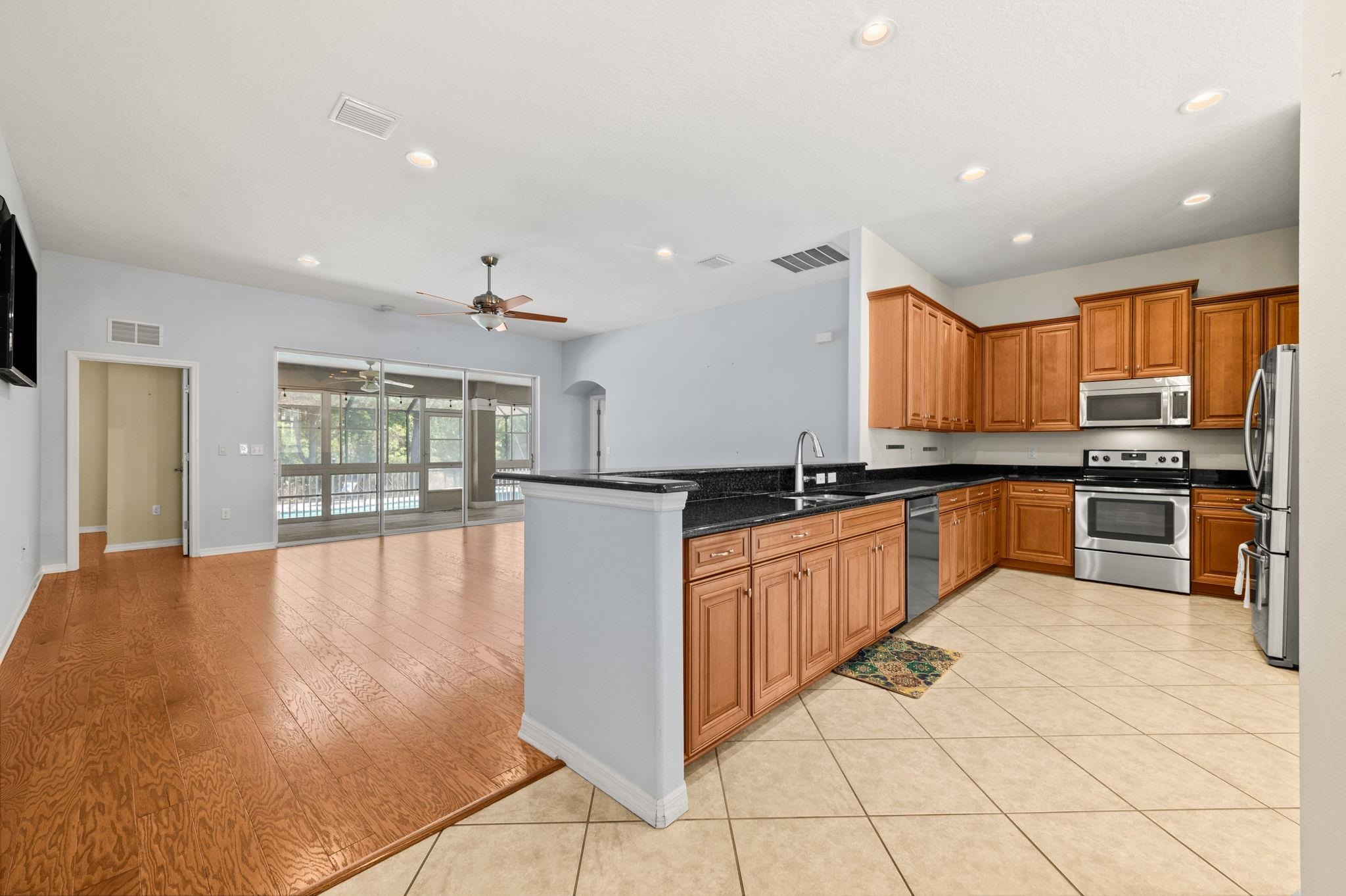 1184 Overdale Road St. Augustine, FL 32080 - Photo 74 of 75 Kitchen featuring wood finish cabinets, stainless steel appliances, arched walkways, open floor plan, and dark stone countertops