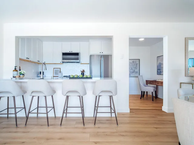 a kitchen with stainless steel appliances granite countertop a stove top oven a sink dishwasher and a dining table with wooden floor