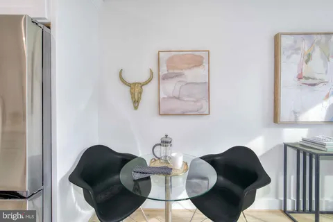 a kitchen with stainless steel appliances kitchen island granite countertop a refrigerator a stove a sink and white cabinets with wooden floor